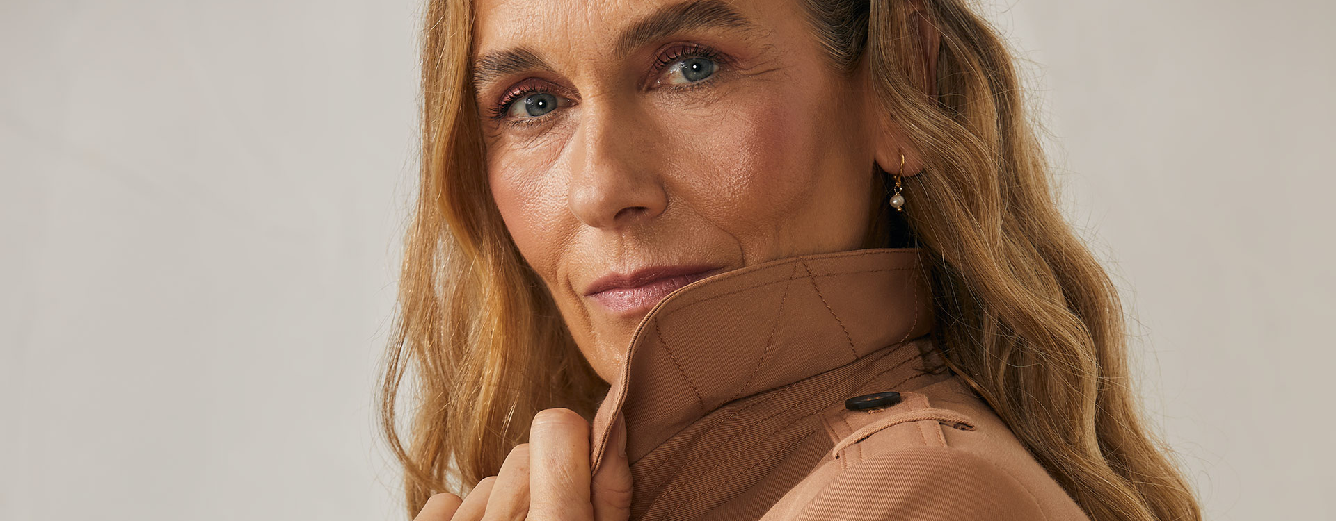 mulher em primeiro plano vestindo trench coat, item da moda atemporal