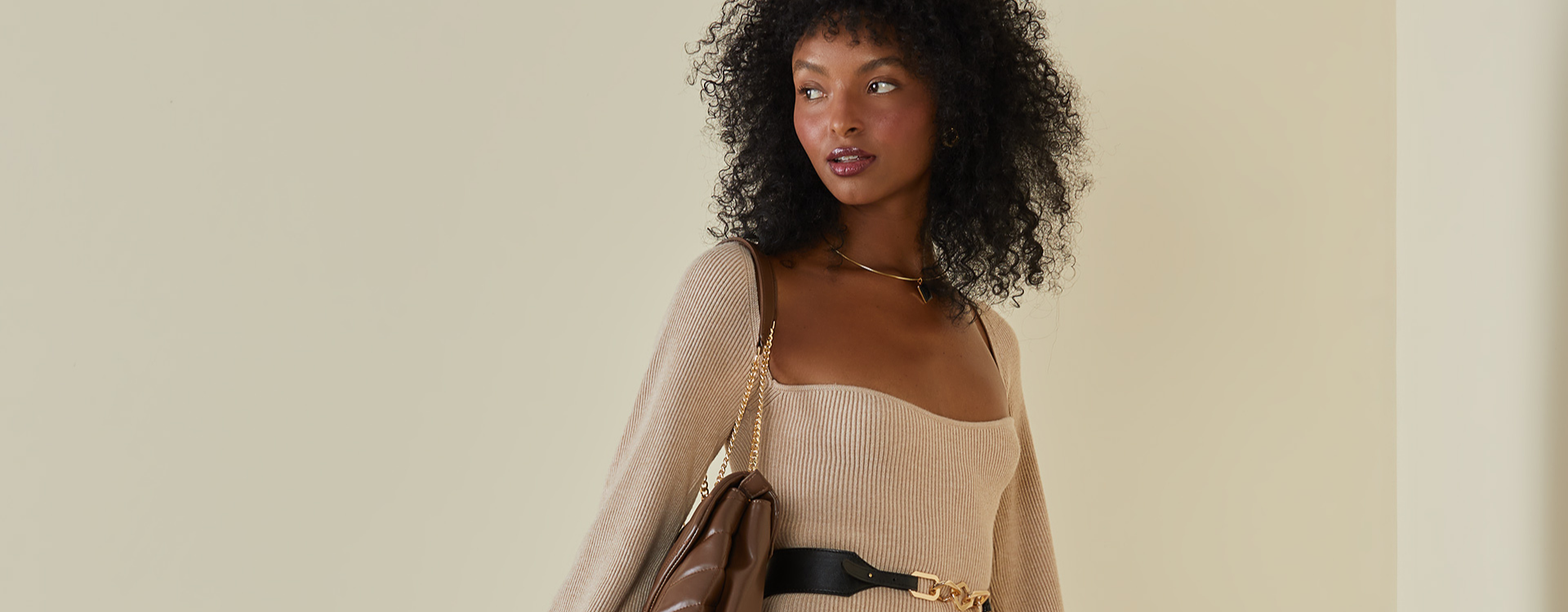 mulher com vestido de manga comprida de tricot bege e bolsa marrom