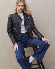 Modelo vestindo jaqueta preta com design clássico e calça jeans.