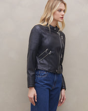 Vista frontal da jaqueta preta com bolsos funcionais e calça jeans.