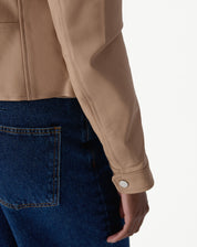 Detalhe do punho da manga com botão de pressão e acabamento do couro pelica em tom rosa claro.