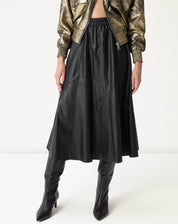 Vista lateral inferior mostrando o caimento midi e os painéis assimétricos da saia statement até a canela