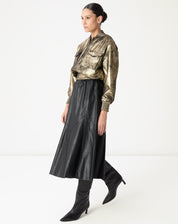 Perfil lateral da saia midi preta evidenciando o volume leve em godê e os recortes assimétricos