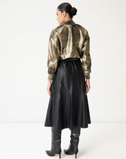 Vista traseira da saia midi preta em poliuretano com costuras e painéis que acentuam o caimento e o cós elástico