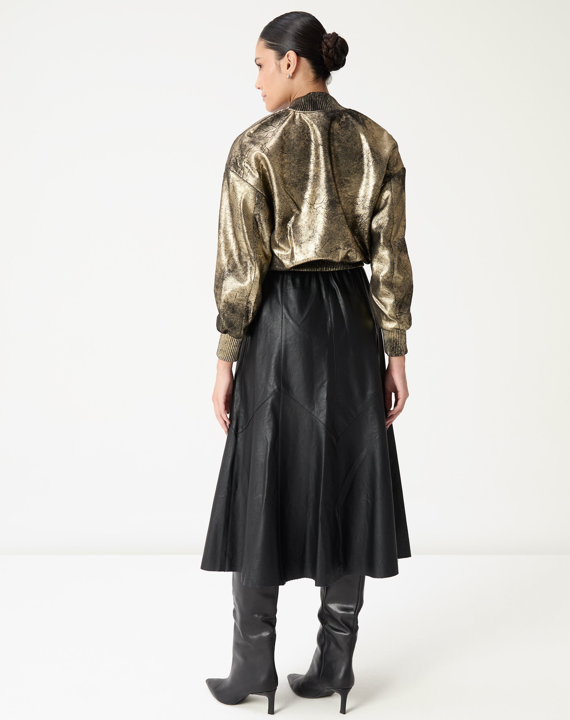 Vista traseira da saia midi preta em poliuretano com costuras e painéis que acentuam o caimento e o cós elástico