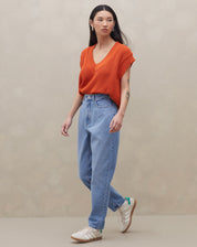 Modelo vestindo calça mom jeans azul clara com blusa laranja, vista frontal.