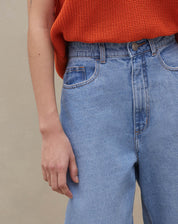 Detalhe do cós alto e fechamento com botão da calça mom jeans.