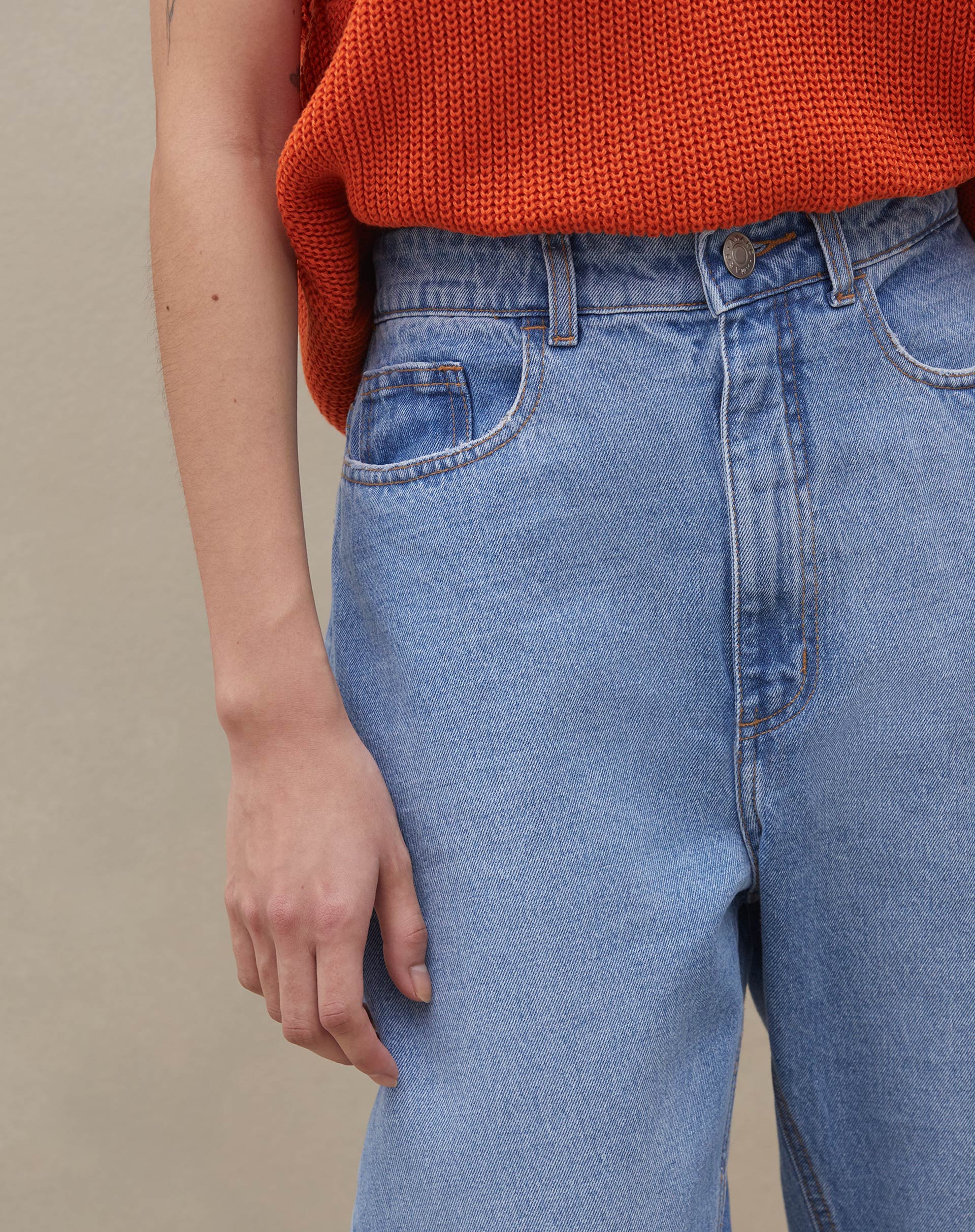 Detalhe do cós alto e fechamento com botão da calça mom jeans.