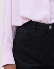 Detalhe do cós e fechamento do shorts de sarja preto.