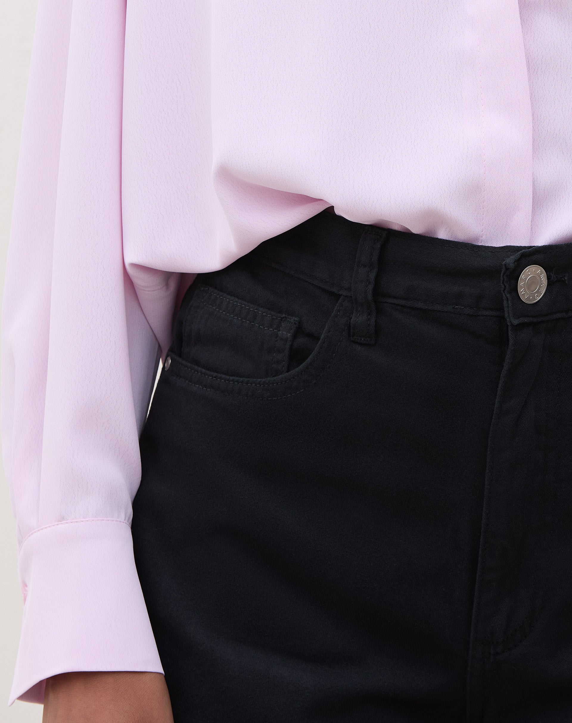 Detalhe do cós e fechamento do shorts de sarja preto.