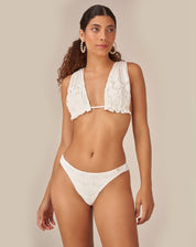 Imagem de um top halter off-white com design elegante, sem aro e sem bojo, visto de lado.