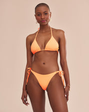 Imagem de um top de biquíni laranja com design cortininha e bojo, exibido em um modelo.