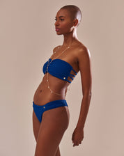 Top bandeau azul vibrante com franzido frontal e tiras entrelaçadas nas costas, visto de lado.