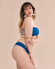 Calcinha de biquíni azul com laterais franzidas vista de perfil.