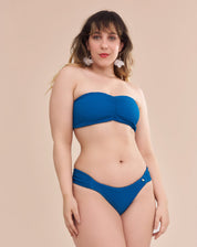 Calcinha de biquíni azul com laterais franzidas em modelo com pele escura vista frontal.