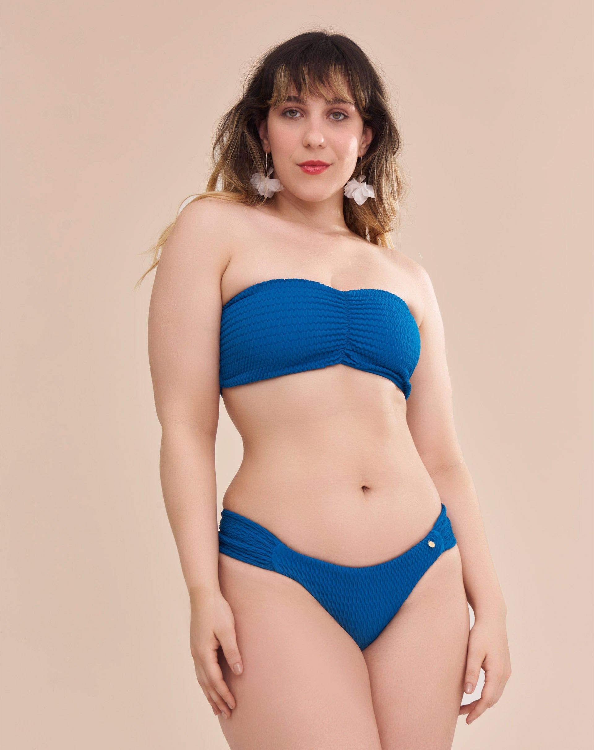 Calcinha de biquíni azul com laterais franzidas em modelo com pele escura vista frontal.