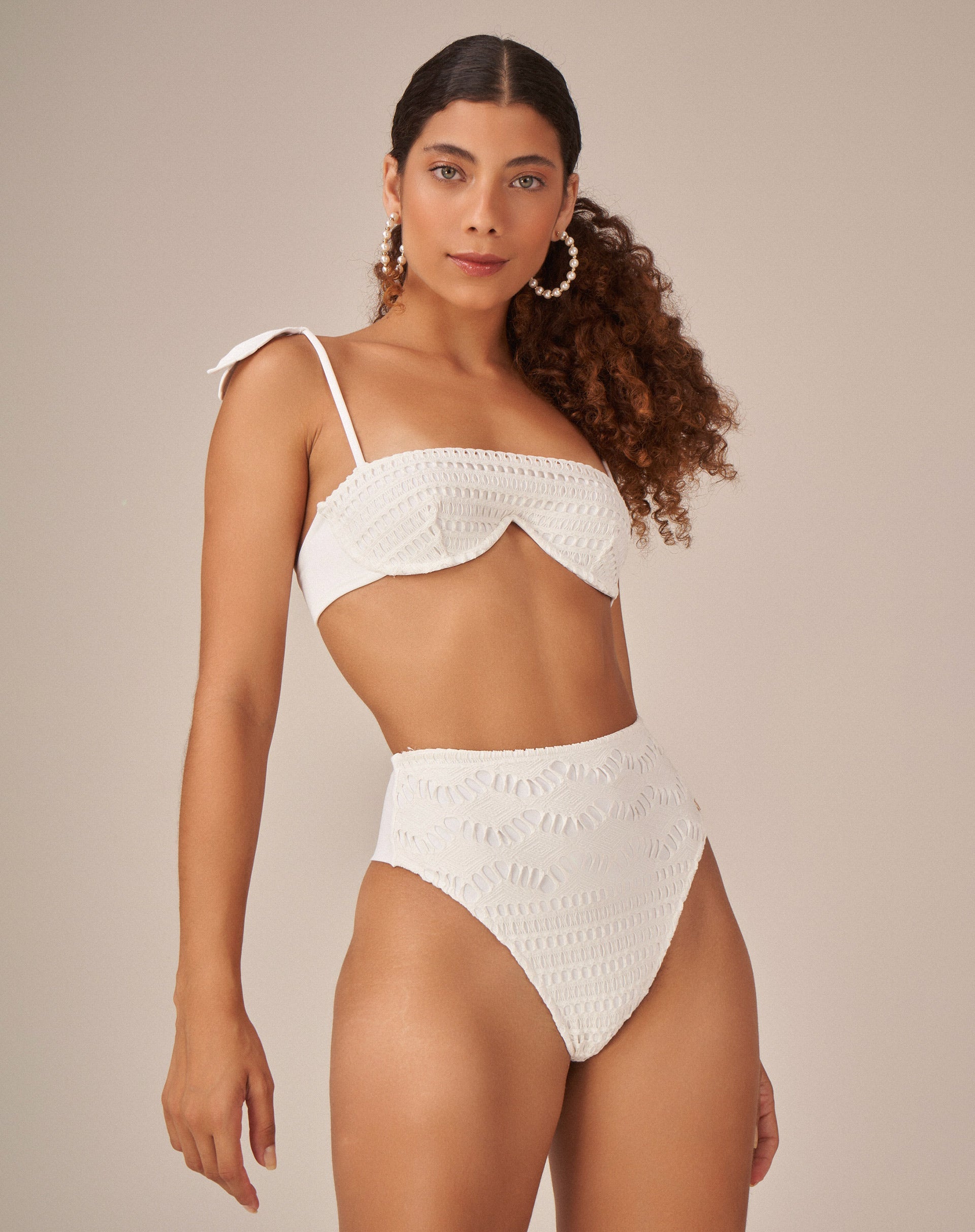 Imagem de uma modelo vestindo uma hot pant off white em tecido de macramê, vista lateral.