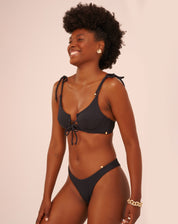 Modelo vestindo top de biquíni preto com aro e alças ajustáveis em forma de laço, vista traseira.