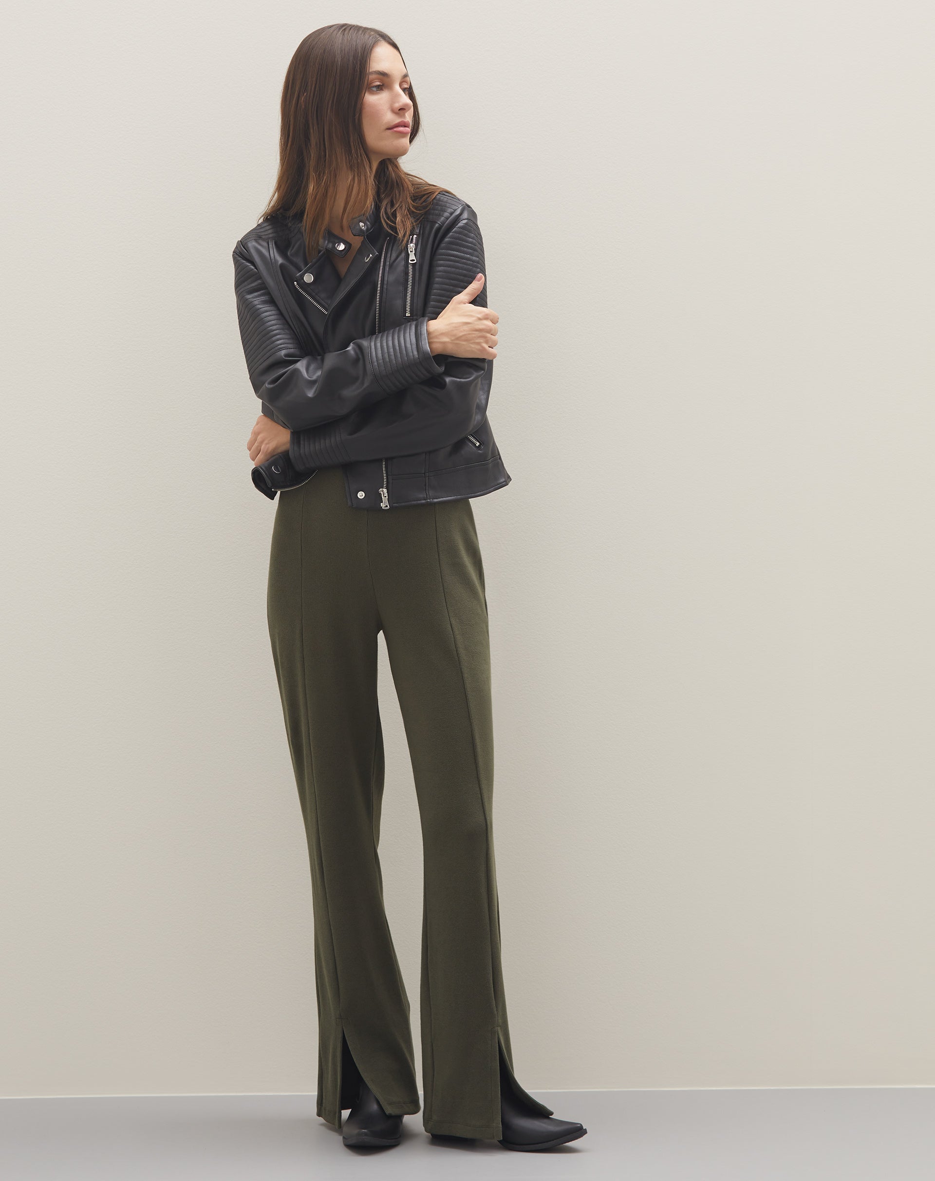 Imagem de uma pessoa usando jaqueta preta e calça verde, complementando o look com botas pretas estilo western.