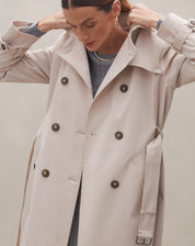 Detalhe do trench coat bege mostrando os botões e o cinto ajustável.