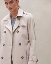Modelo mostrando a parte traseira do trench coat bege com detalhes do cinto.