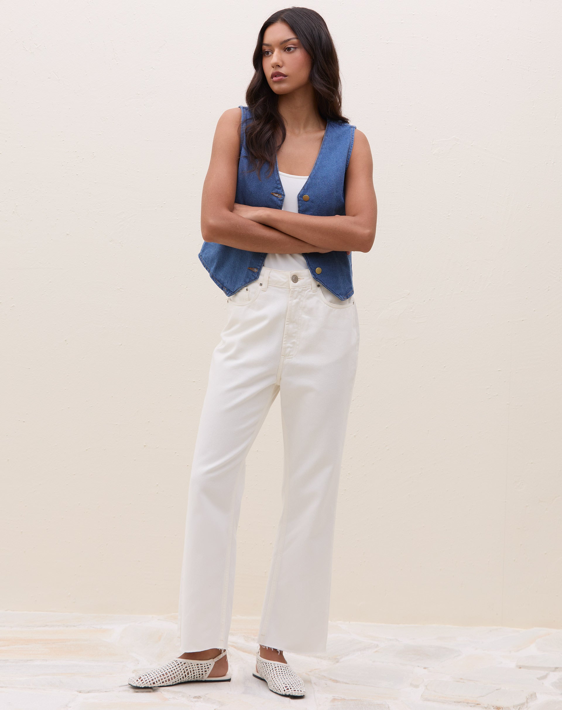 Modelo vestindo calça reta cropped de sarja off-white com colete azul.