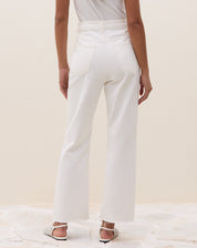 Modelo vestindo calça reta cropped de sarja off-white com blusa branca.