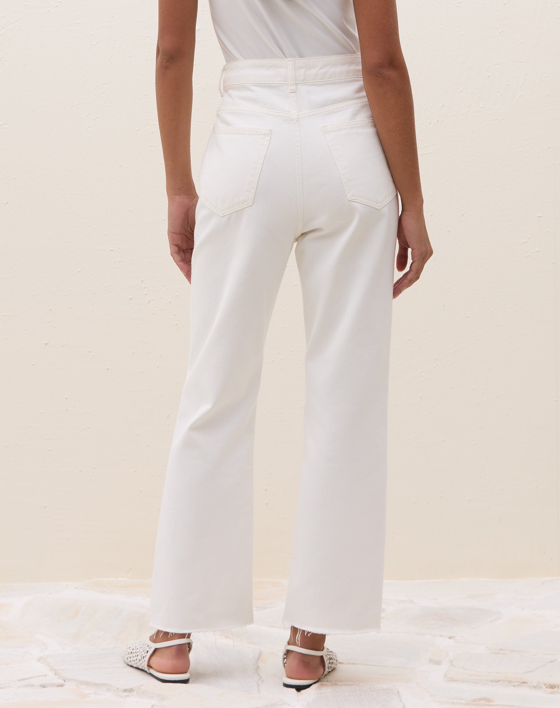 Modelo vestindo calça reta cropped de sarja off-white com blusa branca.