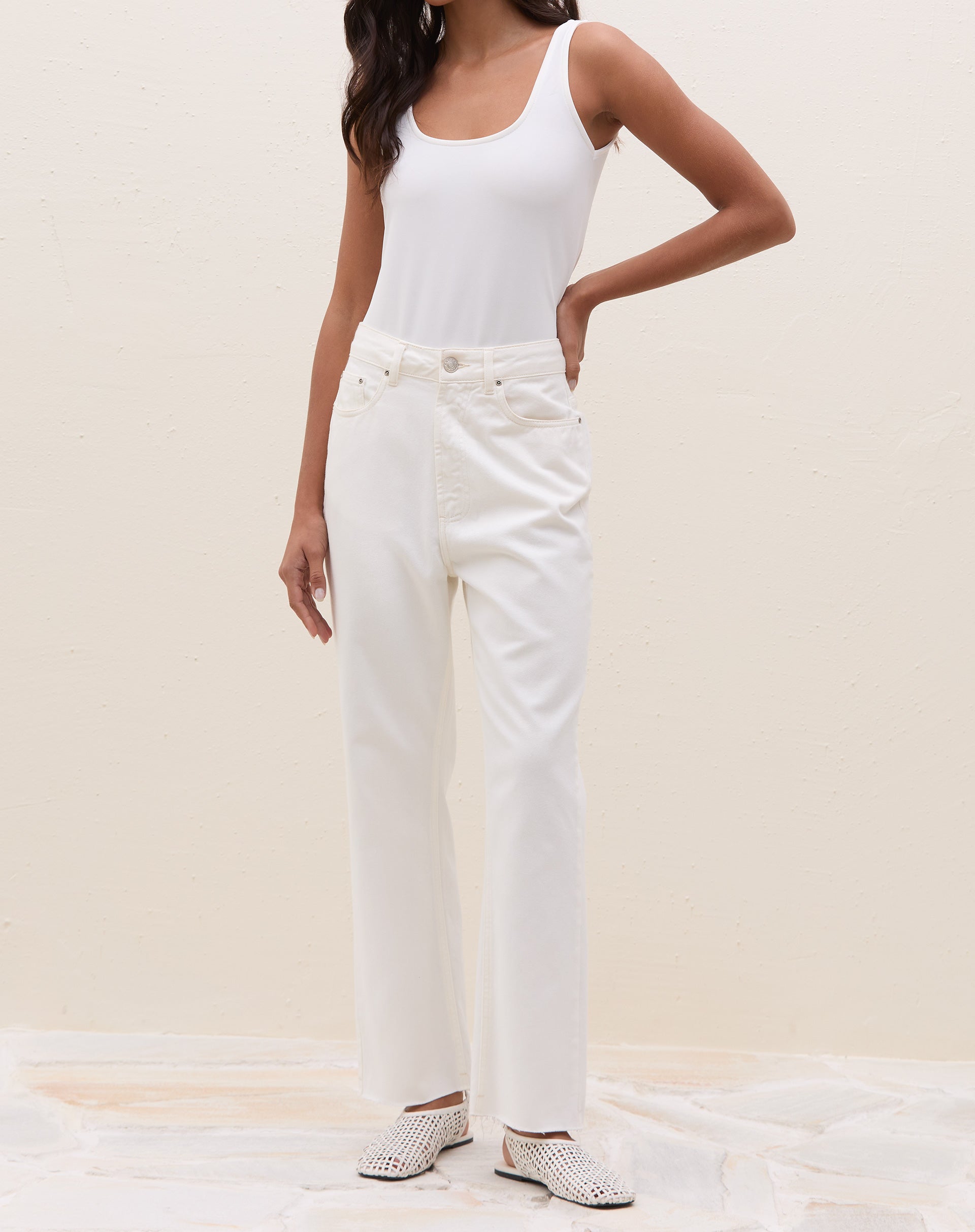 Modelo vestindo calça reta cropped de sarja off-white com colete azul.