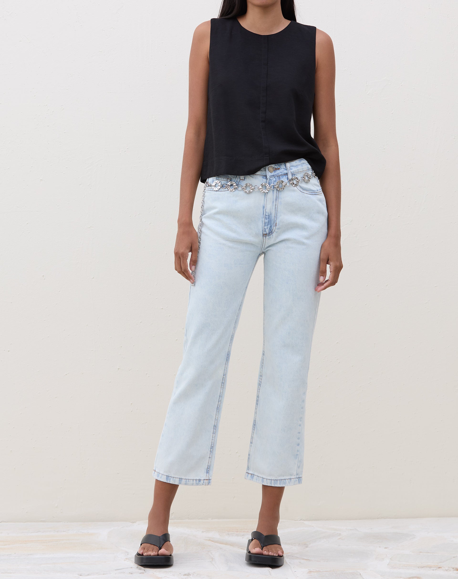 Modelo vestindo calça slim jeans azul claro com blusa preta, vista frontal.