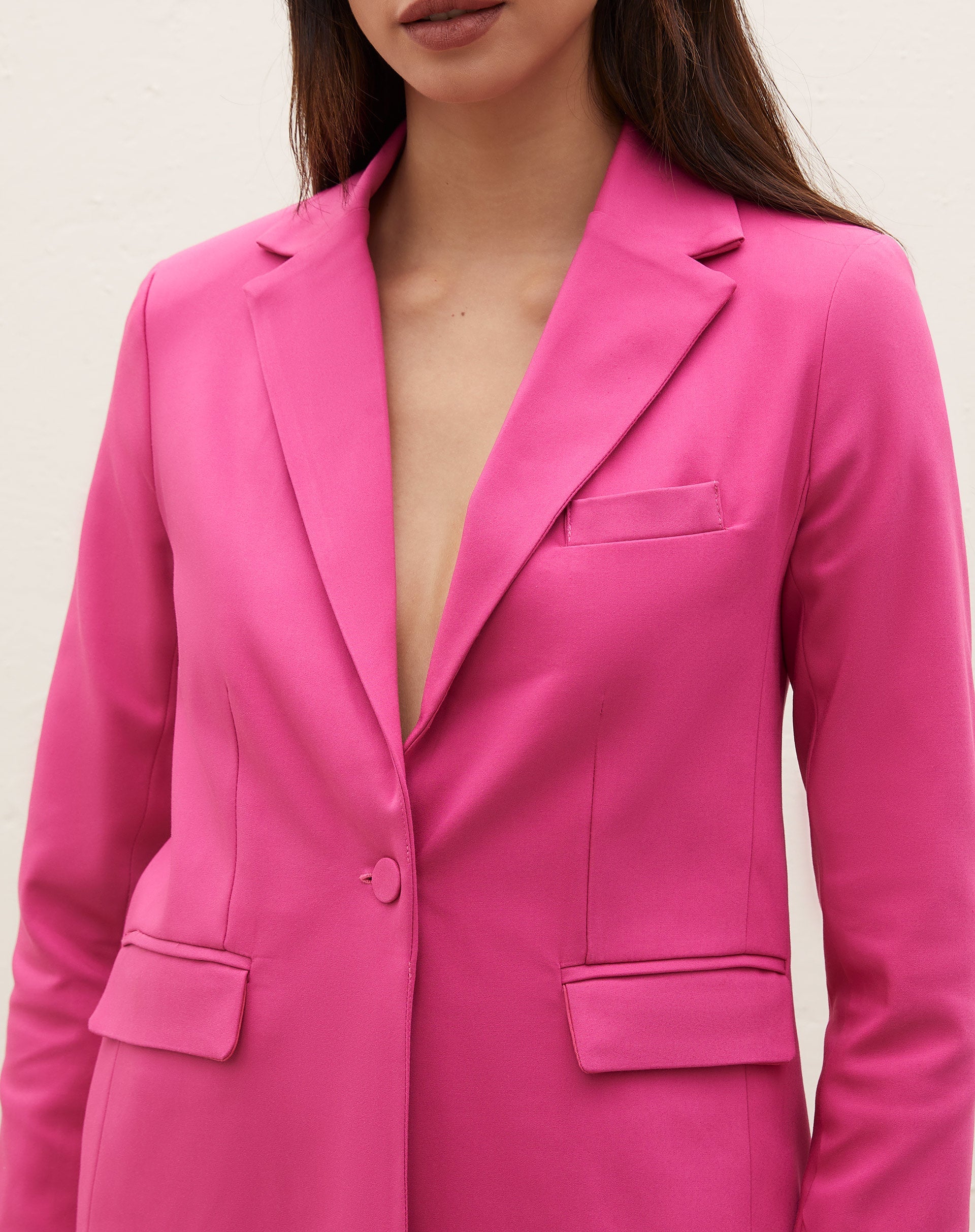 Close-up do blazer rosa com lapela e bolsos com aba, destacando os detalhes.
