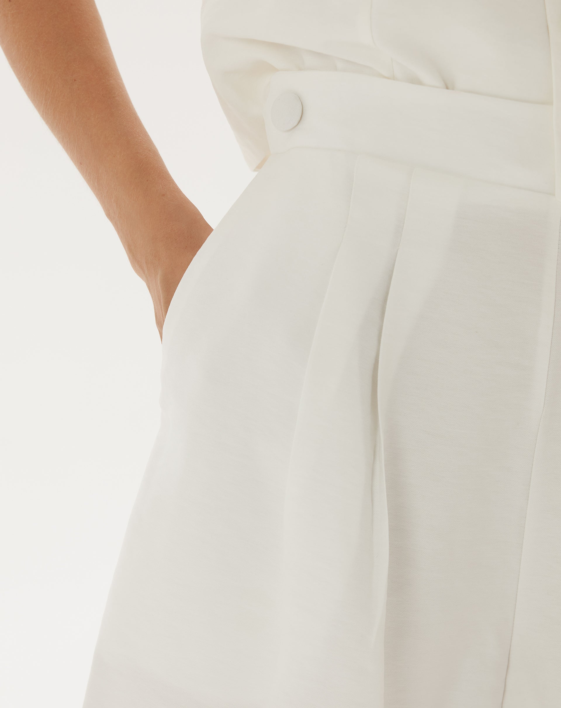 Detalhe do cós alto e fechamento com botão do shorts de alfaiataria.