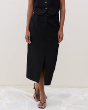 Detalhe da saia midi preta com fenda frontal, mostrando o ajuste na cintura.