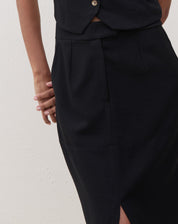 Close-up do detalhe da cintura da saia midi preta, mostrando o acabamento.