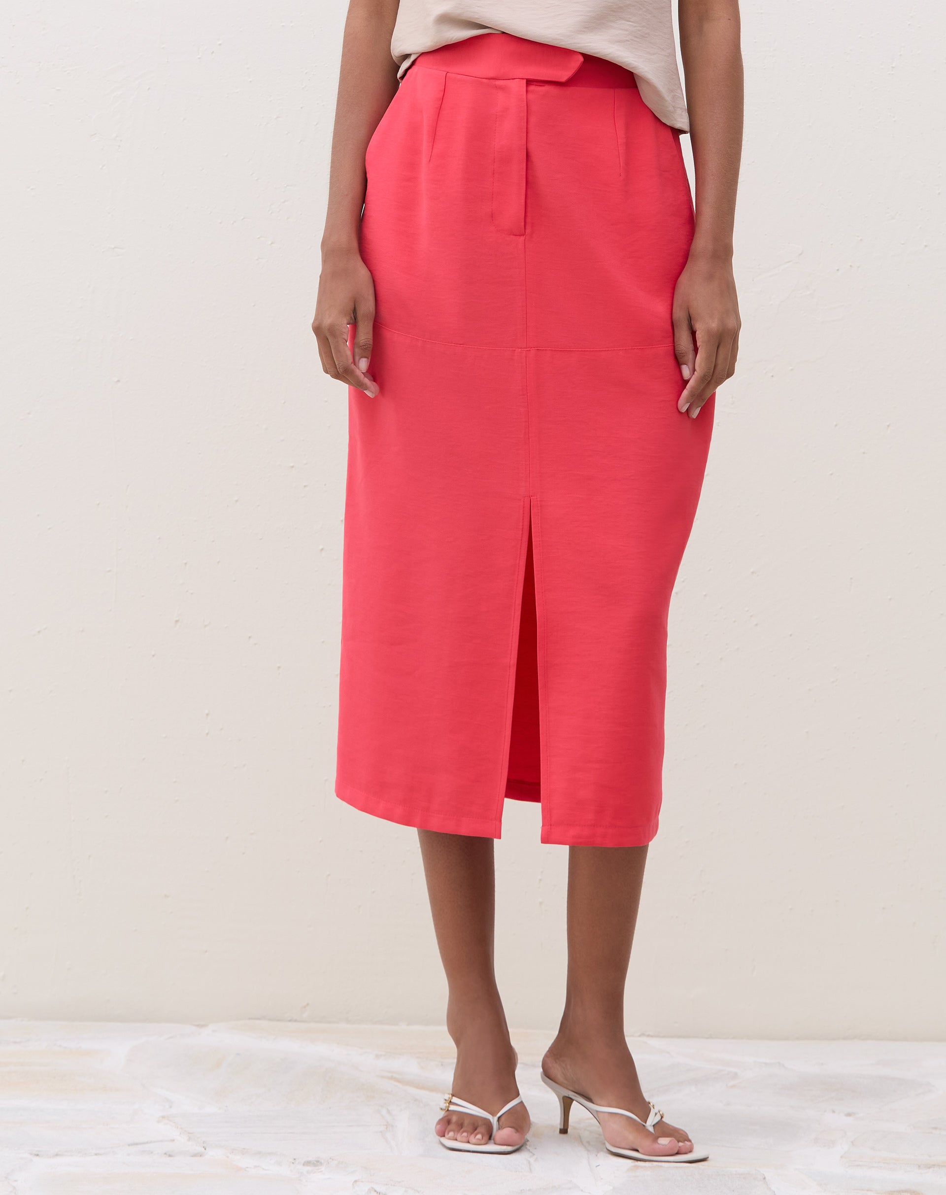 Vista frontal da saia midi coral com fenda, mostrando o ajuste e comprimento.