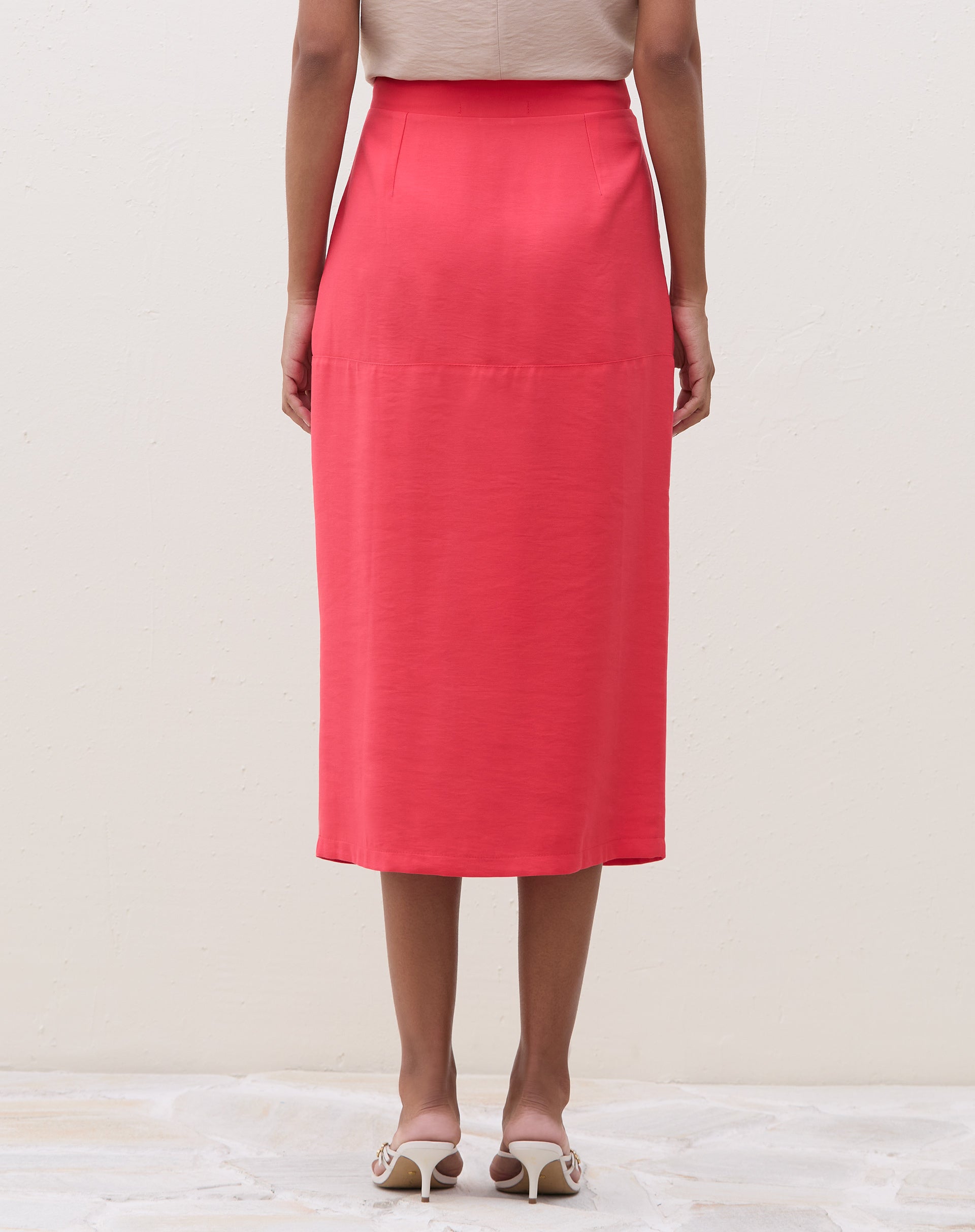 Vista traseira da saia midi coral, destacando o caimento e acabamento.
