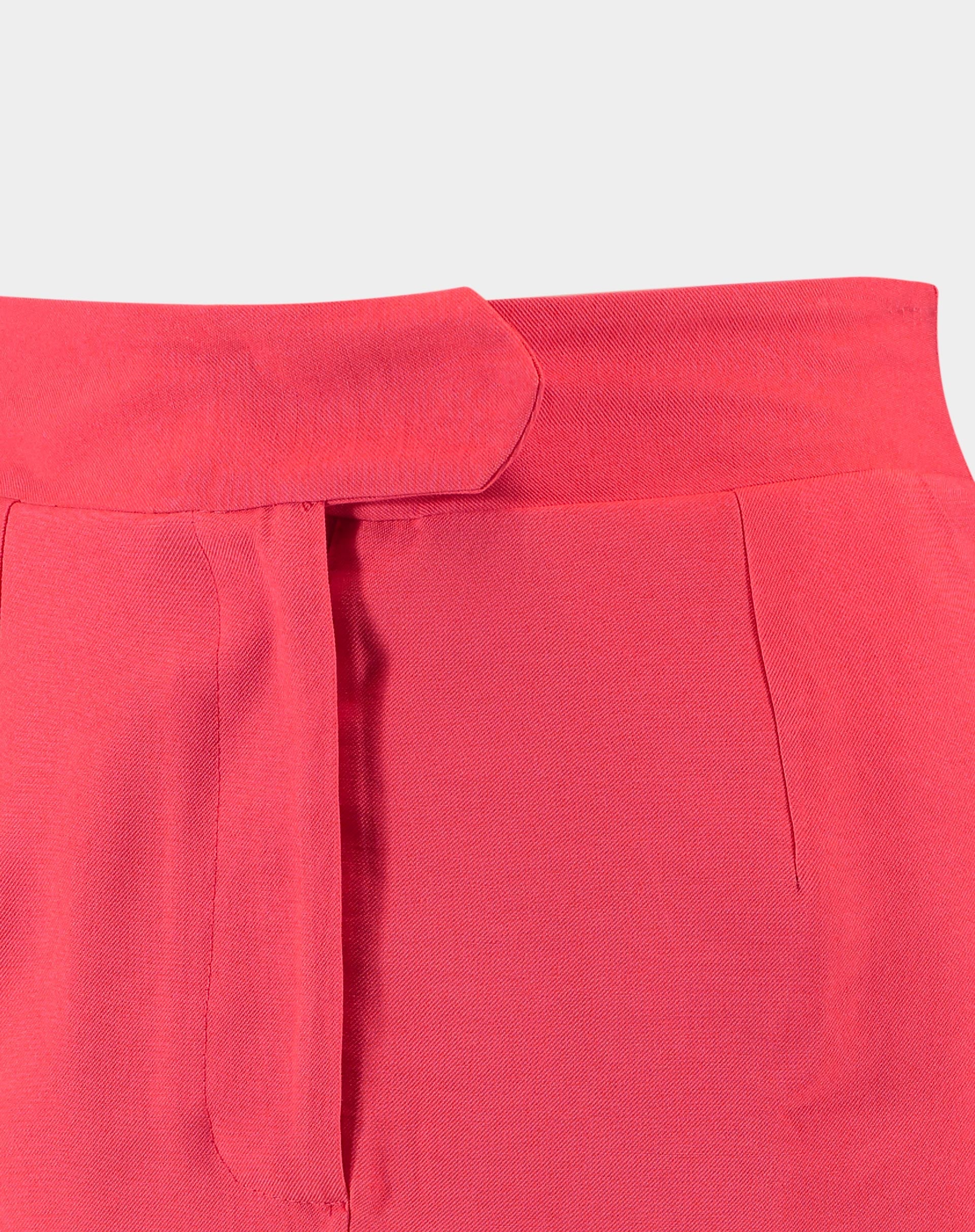 Detalhe do cós e fechamento da saia midi coral em fundo branco.