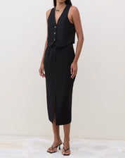 Vista lateral do colete preto de alfaiataria em modelo.