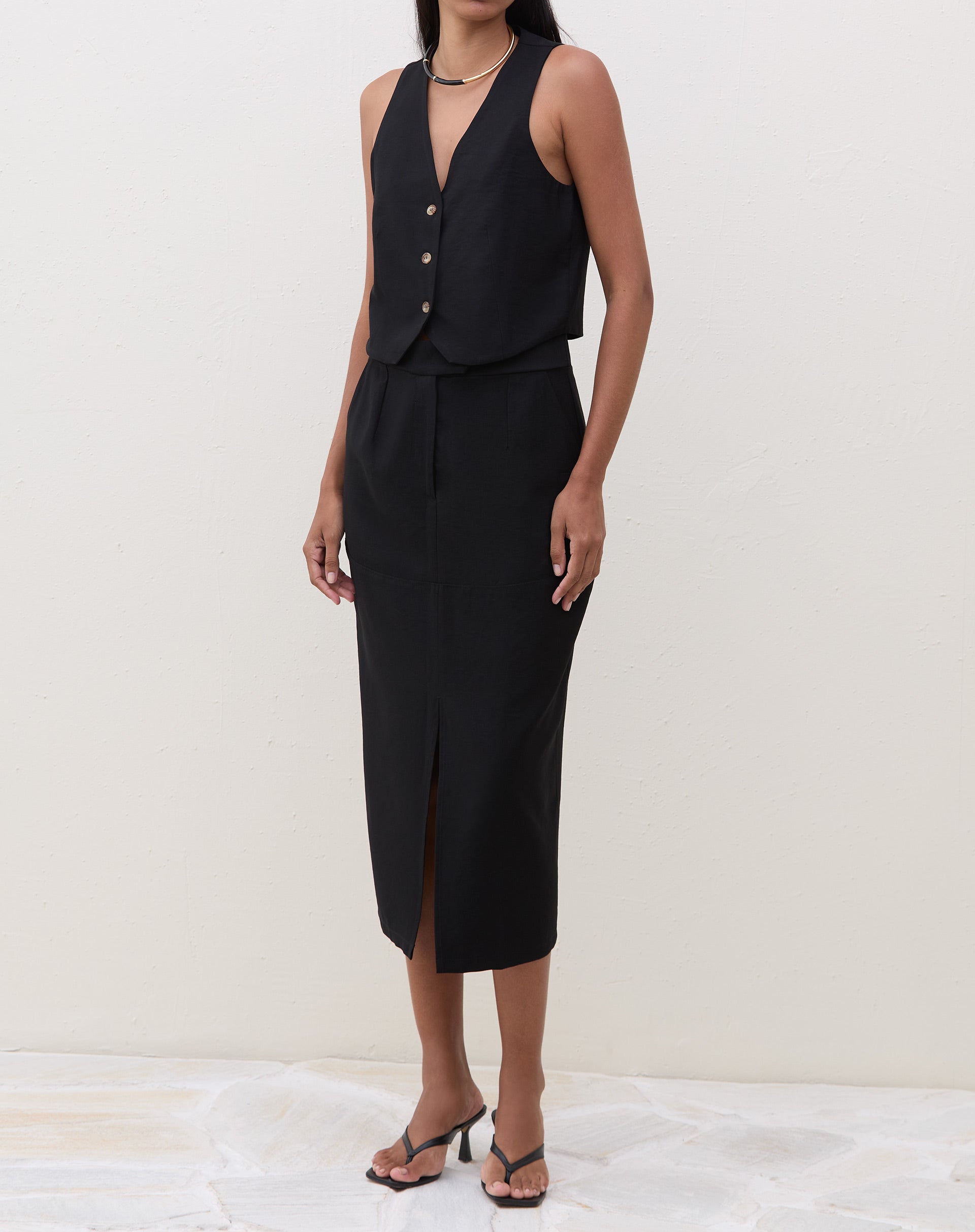 Vista lateral do colete preto de alfaiataria em modelo.