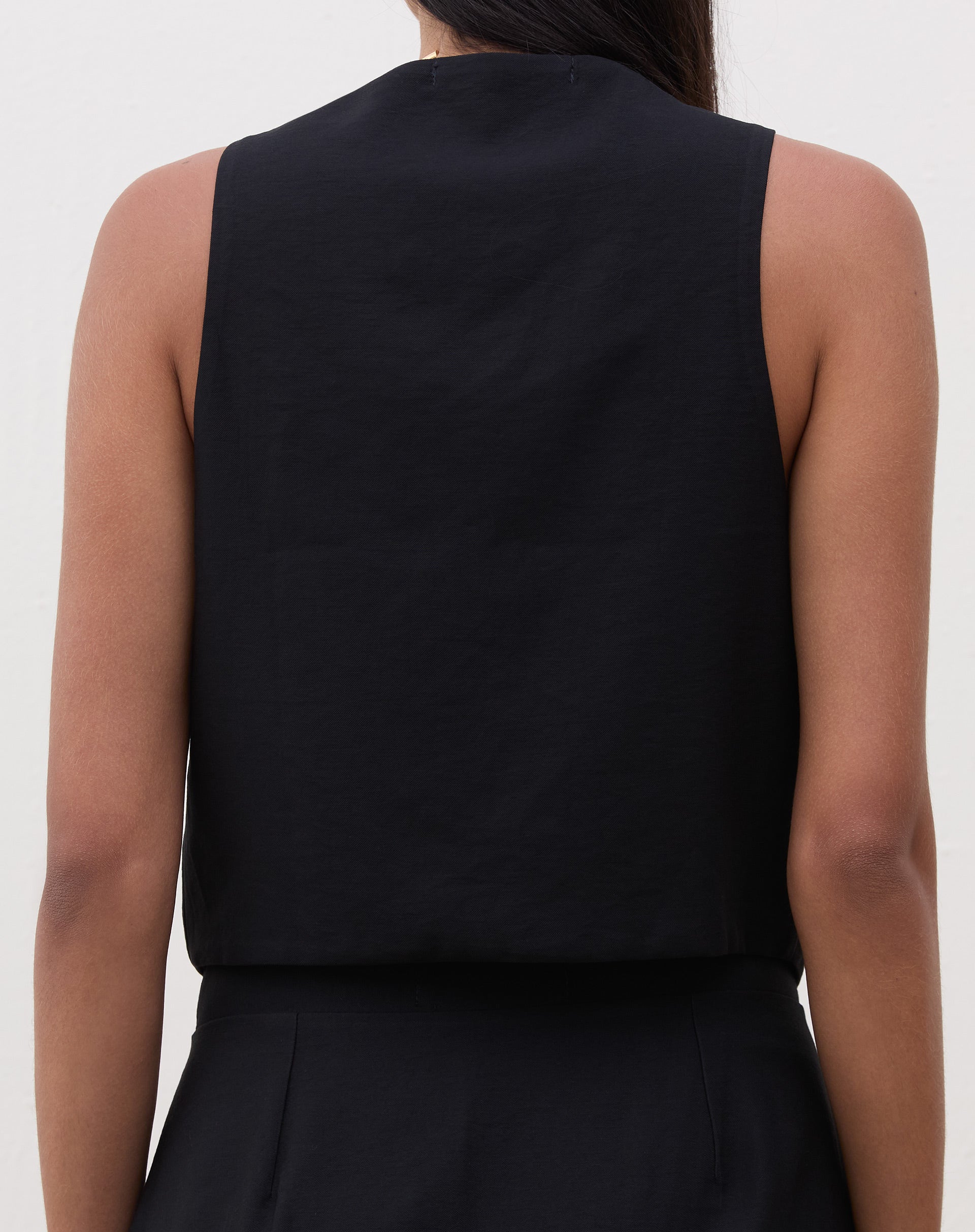 Vista traseira do colete preto de alfaiataria em modelo.