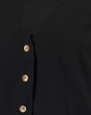 Close-up dos botões do colete preto de alfaiataria.