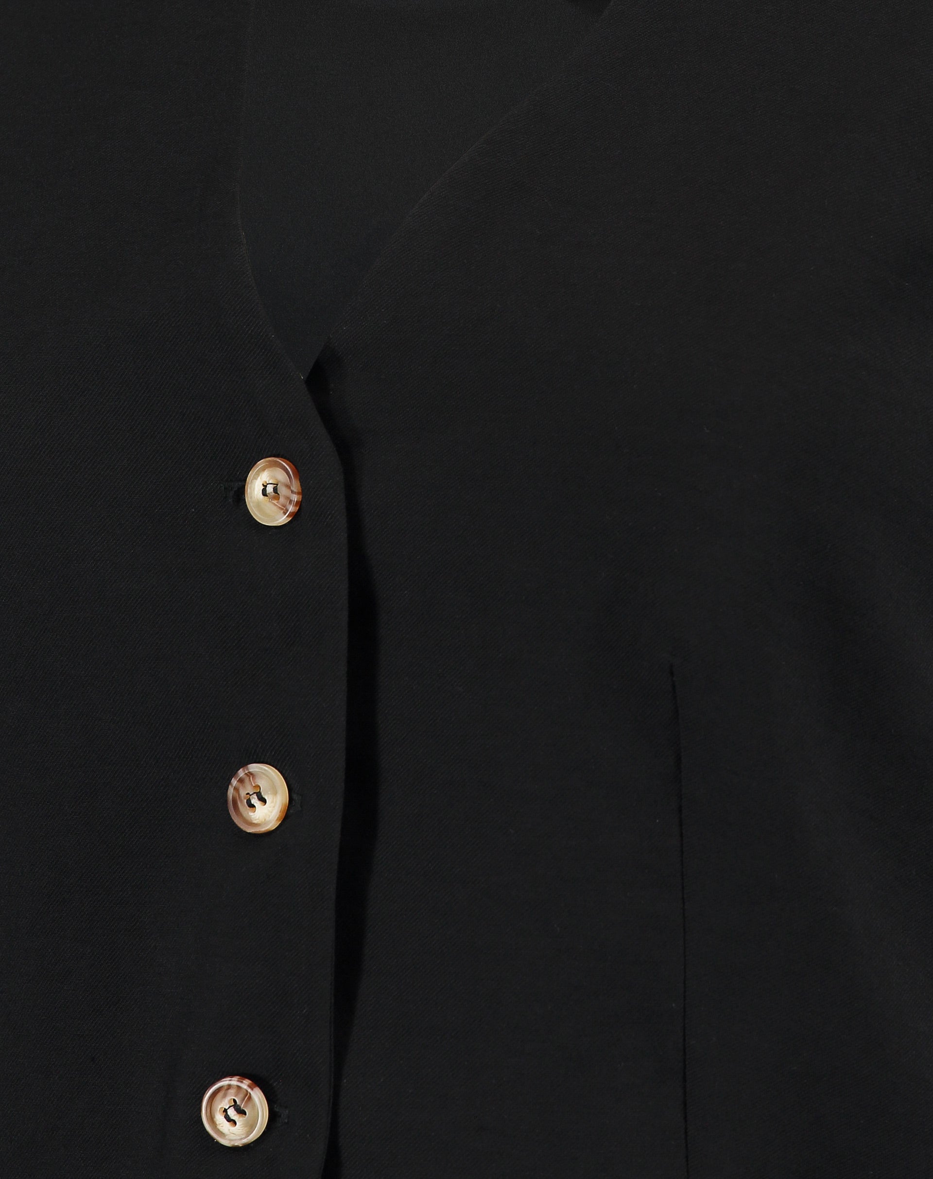 Close-up dos botões do colete preto de alfaiataria.