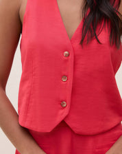 Imagem de um detalhe do colete de alfaiataria vermelho mostrando os botões.