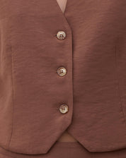 Detalhe do tecido e botões do colete de alfaiataria marrom.