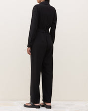 Detalhe da manga longa do macacão preto com botão.