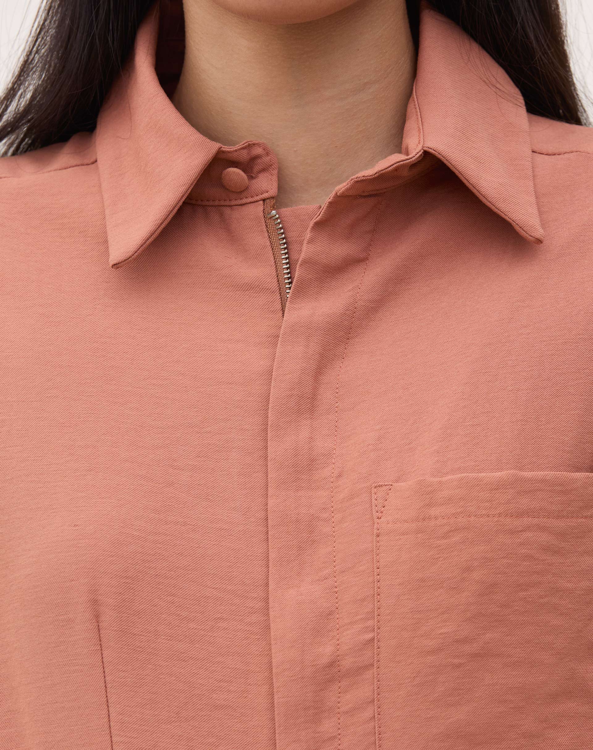 Close-up da gola de camisa do macacão caramelo.