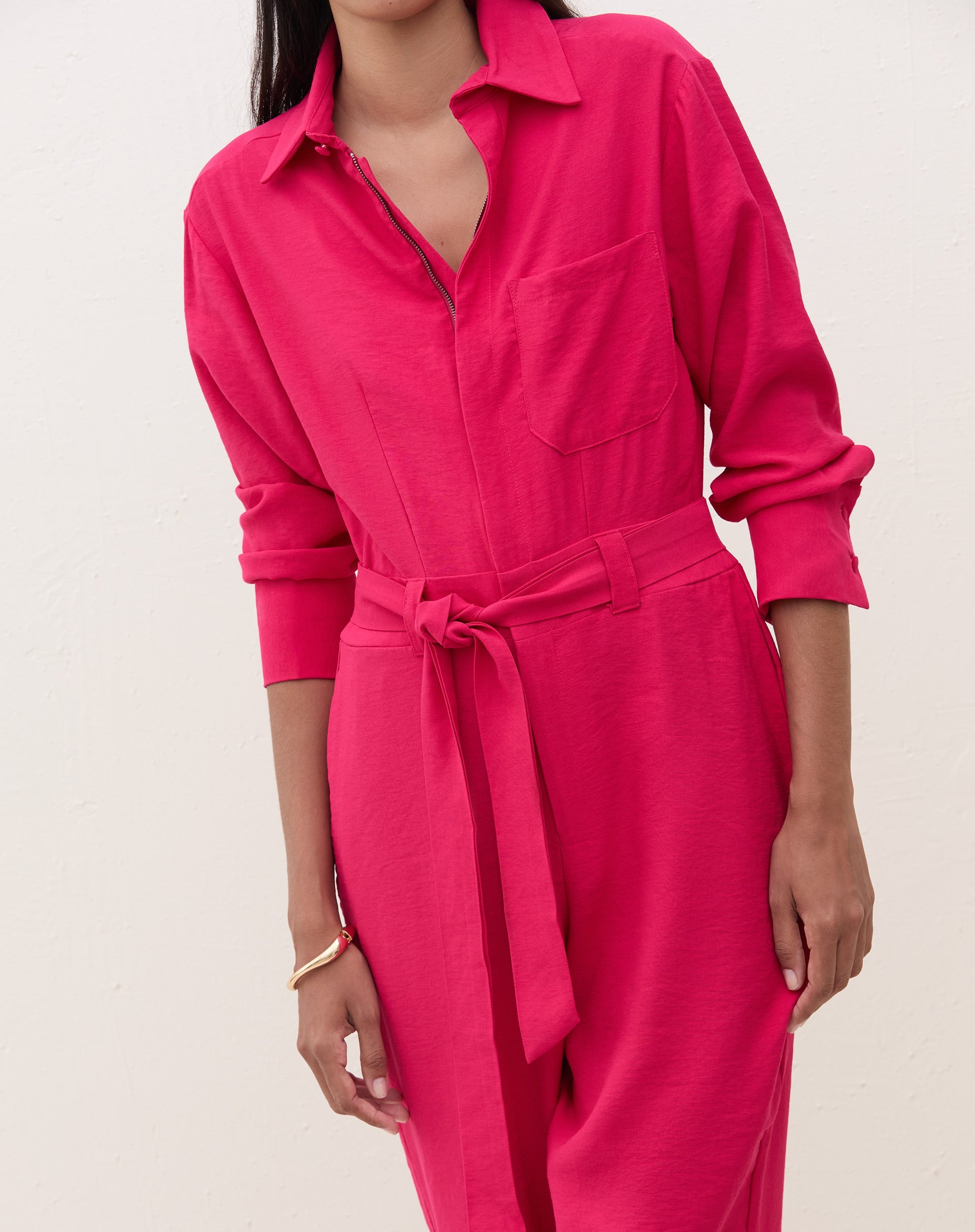 Macacão cereja com gola de camisa e amarração na cintura, visto de frente.