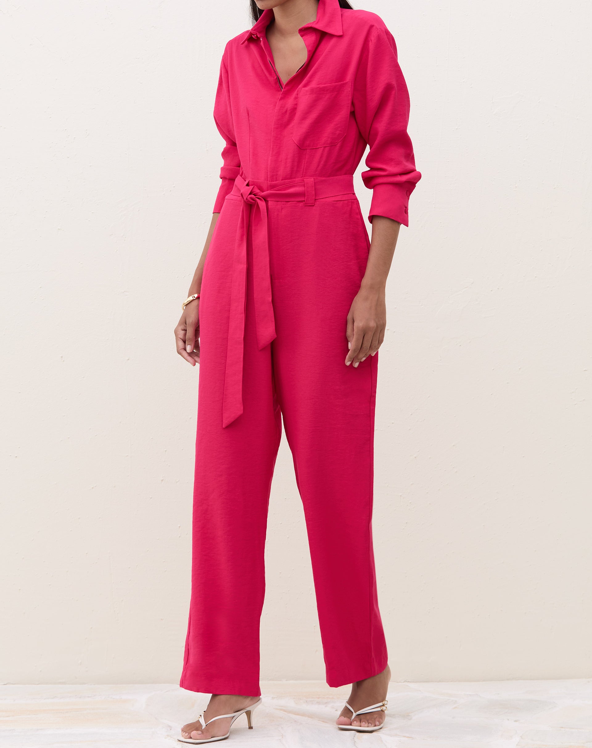 Macacão cereja com mangas longas e pernas retas, modelo em pose lateral.