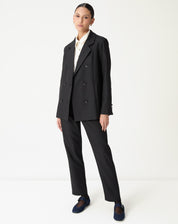 Blazer oversized preto longo em look completo visto de frente com calça reta preta e mocassim azul-marinho, imagem frontal full body.