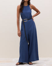 Macacão azul com decote halter e cintura ajustada por cinto, visto de frente.